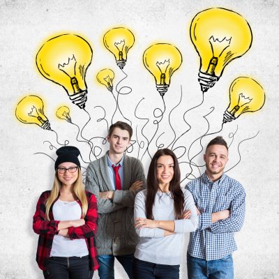 Attractive young team on concrete background with drawn light bulbs. Creative idea concept